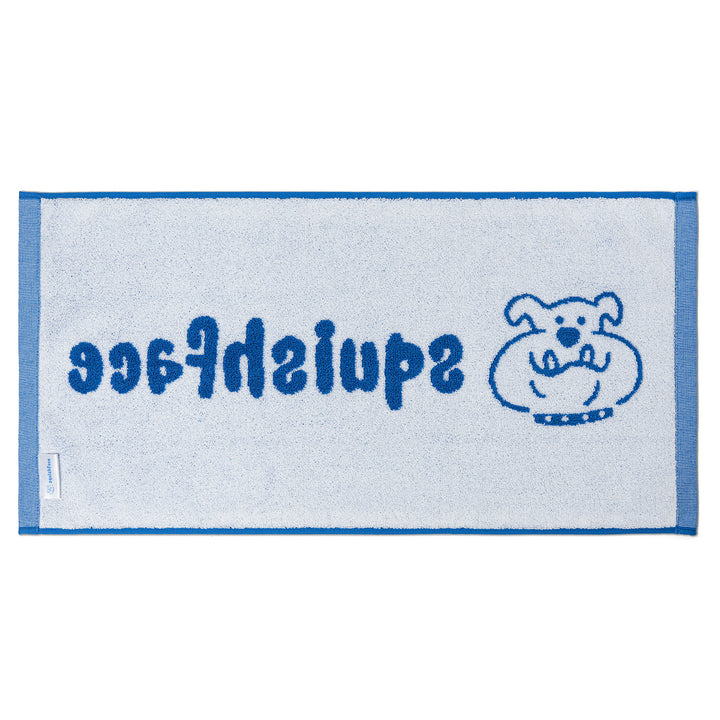 White towel with blue border and text, featuring a cartoon dog illustration on a white background.